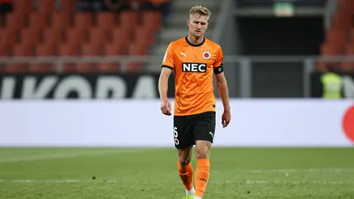 A tight action shot of an anonymous NEC Nijmegen player in his orange jersey with black shorts, looking frustrated as he...