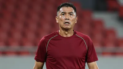 Middle-aged, athletic coach, mid-40s, intense gaze, waist-up, wearing an unmarked dark-red shirt with subtle green...