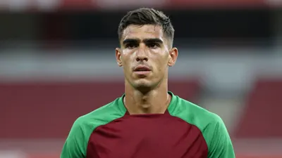 Mid-30s athletic midfielder, lean build, focused expression, head-and-shoulders shot, dark red and green training top...