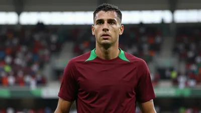 Mid-20s forward, athletic build, intense gaze, sweat-glazed forehead, wearing a plain dark-red and green training top...