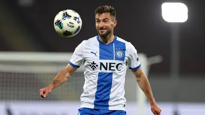 A photorealistic image of a NEC Nijmegen defender, aged 25-30, with a rugged build, in a white jersey with a blue stripe...